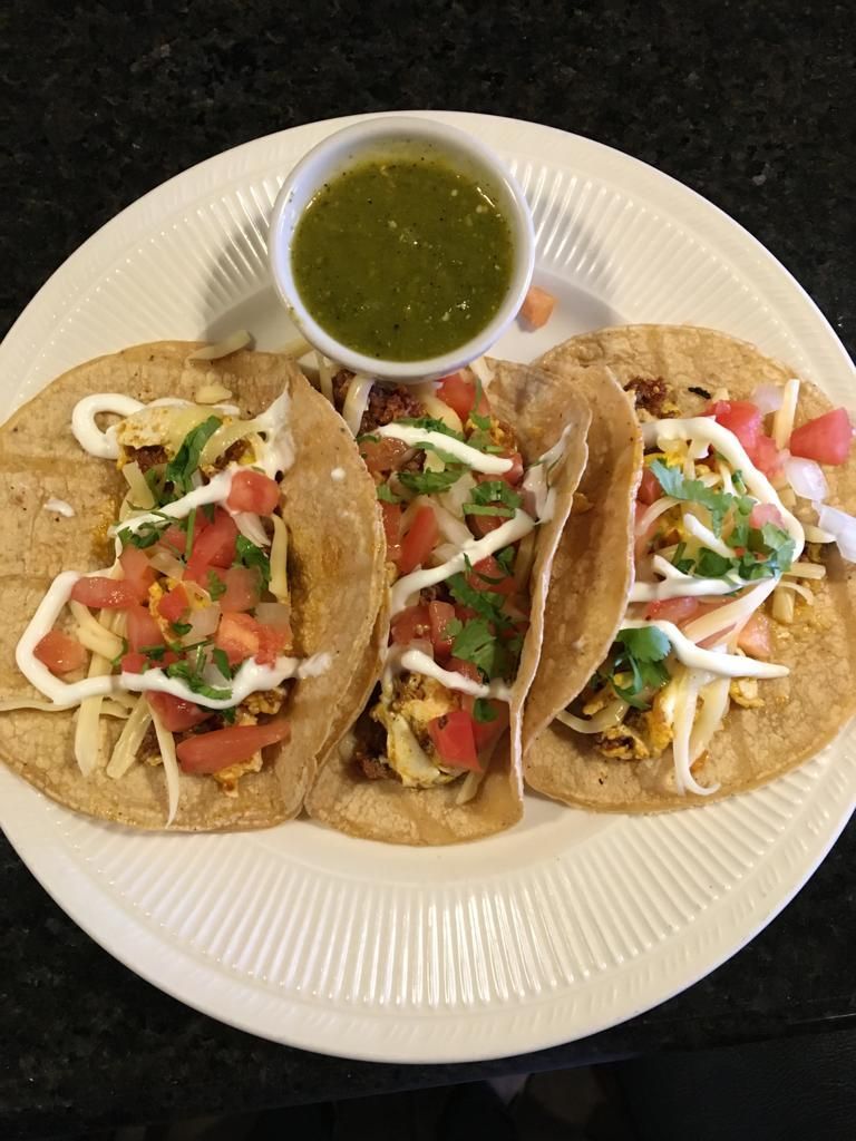 A white plate topped with three tacos and a dipping sauce.